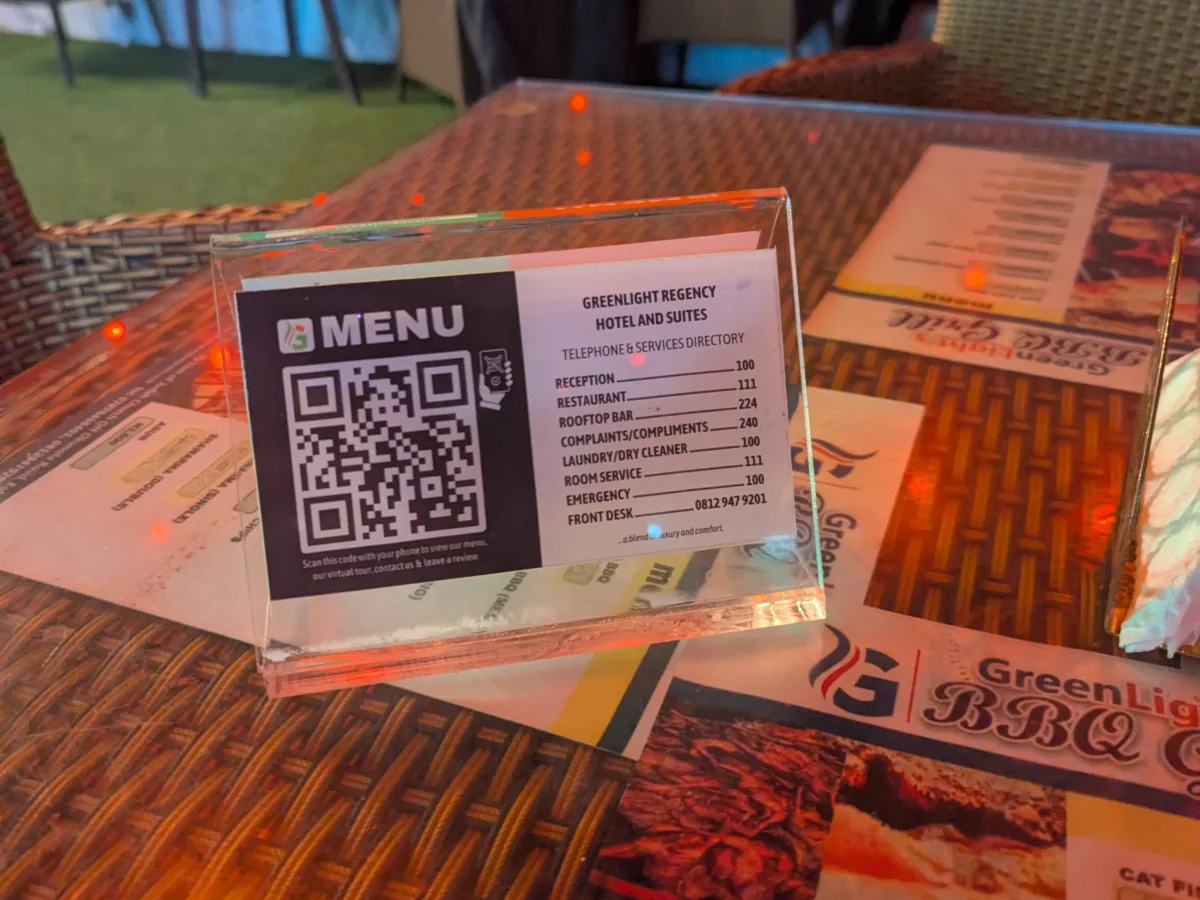 An acrylic QR table stand on site at Greenlight Regency Hotel & Suites, linking directly to the live page above.